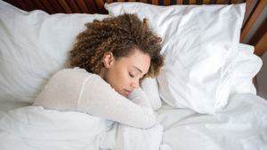 Tired African American woman sleeping in bed at home