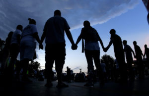 People stand in prayer after marching about a mile to the police station to protest the shooting of Michael Brown in Ferguson, Mo., in August.