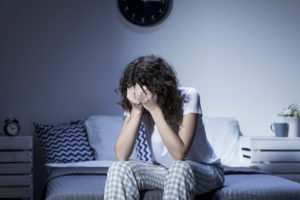 Depression and insomnia- young woman sitting on bed